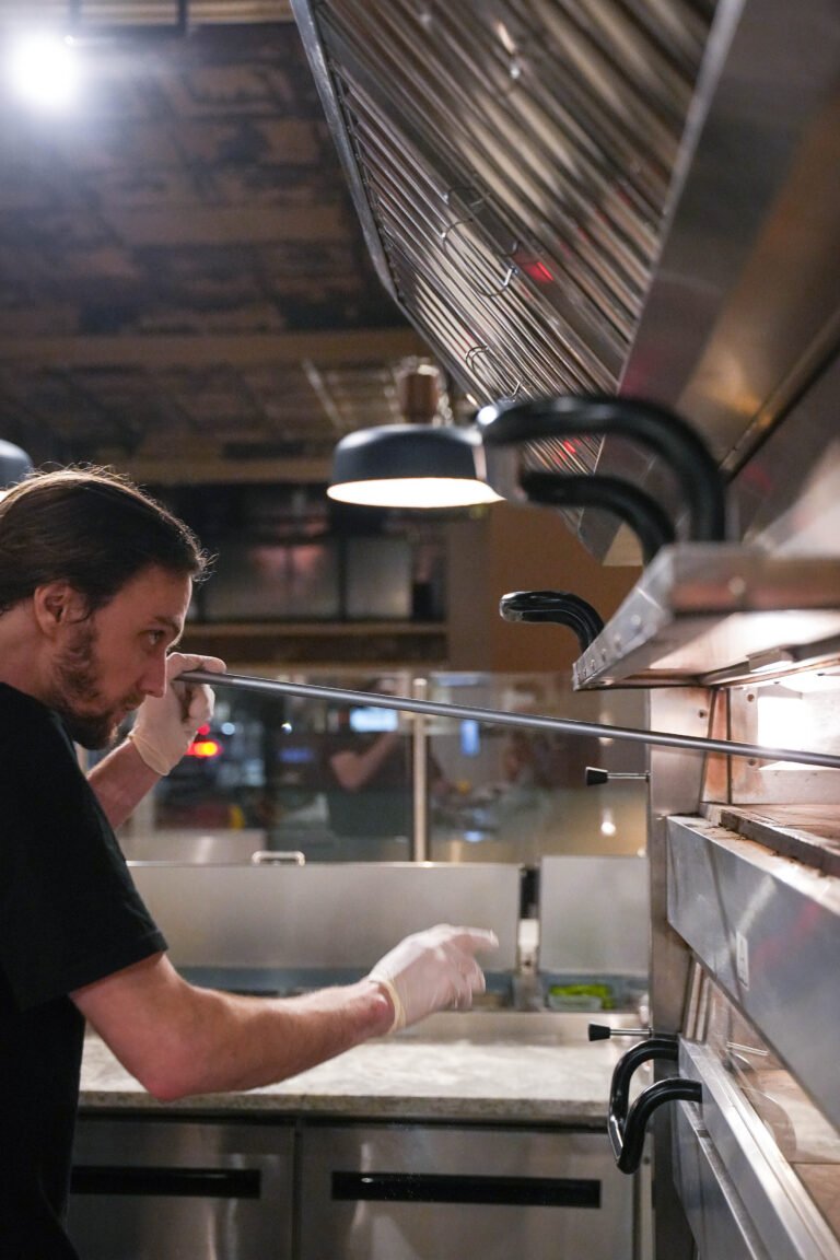 A Black Dog Pizza cook working beside the oven